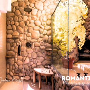 a shower with a stone wall and a bench